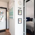 Entryway with door, wall art, and view into bedroom with bed.