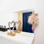 Mirror with heart figures and doll hanger on white shelf.