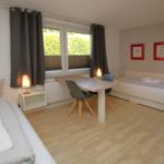 Zimmer mit zwei Betten, Tisch und Stühlen, Fenster mit Jalousien und Wandbildern.