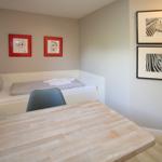 Schlafzimmer mit Bett, Tisch und Wandbildern.