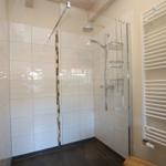 Shower with glass enclosure, shower head, and heater on the wall
