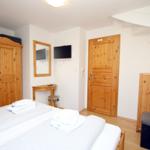 Schlafzimmer mit Holzmöbeln, Bett, Fernseher und Tür.
