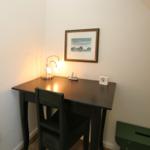 Desk with chair, lamp, clock, and picture on the wall.