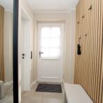 Eingangsbereich mit Holzwand, Bänken und Haken für Regenbekleidung.