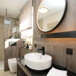 Badezimmer mit Waschbecken, Spiegel und Dusche.