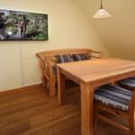 Esszimmer mit Holztisch, Stühlen und Sofa. Wandfernseher an der Wand.