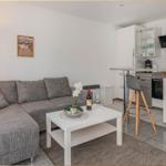 Wohnbereich mit Sofa, Tisch und Küchenzeile mit Hochstuhl.
