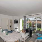 Wohnküche mit Essbereich, Sofa, Fernseher und Blick auf Garten.