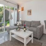 Wohnzimmer mit grauem Sofa, weißem Tisch und Blick auf die Terrasse.