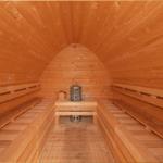 Holzsauna mit Sitzbänken und Heizung im Zentrum.