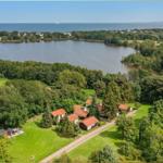 Liegenschaft mit mehreren Häusern am See, umgeben von Wald und Grünflächen.