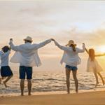 Familie springt am Strand im Sonnenuntergang Hand in Hand.