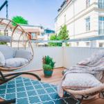 Terrace with hanging chair and lounge chair, blue rug, and plant.