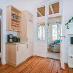Kitchen with wooden floor, open shelves, and view into living and sleeping rooms.
