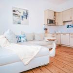 Living room with sofa, kitchenette, and wooden floor.