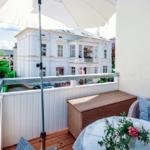 Terrace with table, chairs, and umbrella. View of a white house with balcony.