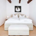 Bedroom with white bed, wooden beams, and wall picture of a ballerina.