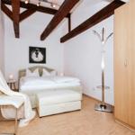 Bedroom with bed, chair, coat stand, and wardrobe under wooden beam ceiling.