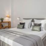 A bed with pillows, sheets, and a blanket. Next to the bed is a nightstand with a lamp.