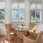 A room with four chairs around a round table and large windows with a view outside.