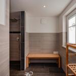 Dusche mit Sitzbank und Holzbank vor Fenster