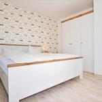 Schlafzimmer mit Bett, Schrank und Tapete mit Schiffsmotiven.