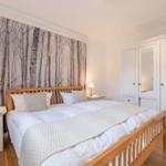 Bedroom with bed, nightstands, and wardrobe. Wallpaper shows trees.