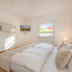 Bedroom with bed, wall art, window, and TV.