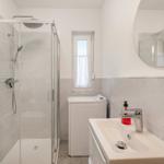 Bathroom with shower, washing machine, and sink with mirror.