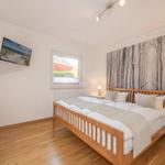 Bedroom with wooden bed, wall art, and TV mounted on the wall.