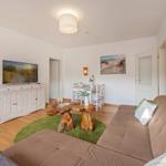 Living room with sofa, wooden table, and TV. Dining area with table and chairs.