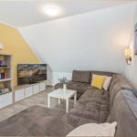 Wohnzimmer mit Sofa, Fernseher und Bücherregal an gelber Wand.