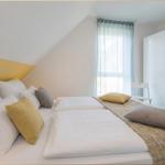 Schlafzimmer mit Doppelbett, gelbem Akzentwand und Fenster mit Vorhängen.