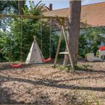 Kinderspielplatz mit Schaukel, Tipi und Rutschbahn im Garten.
