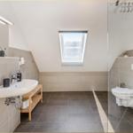 Badezimmer mit Dusche, Toilette und Waschbecken unter Dachschrägen.