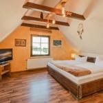 Schlafzimmer mit Dachschrägen, Holzbett, TV und Fenster.