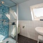 Badezimmer mit Dusche, Waschbecken und Dachfenster.
