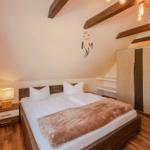 Schlafzimmer mit Doppelbett, Holzboden und Holzbalken an der Decke.