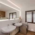 Badezimmer mit zwei Waschbecken, Spiegel und Waschmaschine.