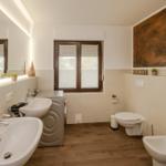 Bad mit zwei Waschbecken, Toilette, Waschmaschine und Fenster