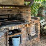 Steinofen mit Grill, Werkzeug und Sitzbank im Garten