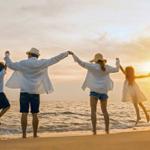 Familie springt am Strand bei Sonnenuntergang zusammengehalten.