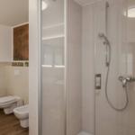 Bad mit Dusche, WC und Bidet. Holzfußboden und Fenster mit Jalousie.