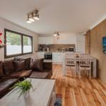 Wohnzimmer mit Sofa, Esstisch und Küche. Holzboden und Wandbild.