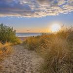 Sandweg durch Dünen zur Strandpromenade bei Sonnenuntergang