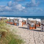Strandkörbe auf Sandstrand mit Blick auf Meer und Himmel.