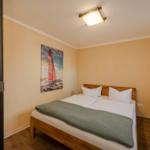 Schlafzimmer mit Bett, Wandbild und Kleiderständer.