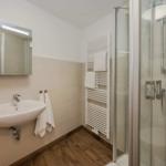 Badezimmer mit Dusche, Waschbecken und Heizkörper.