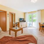Wohn- und Essbereich mit TV, Terrasse und Essgruppe. Holzmöbel und warme Wandfarbe.