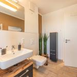 Badezimmer mit Waschbecken, Toilette und Spiegelschrank. Holzoptik und moderne Einrichtung.